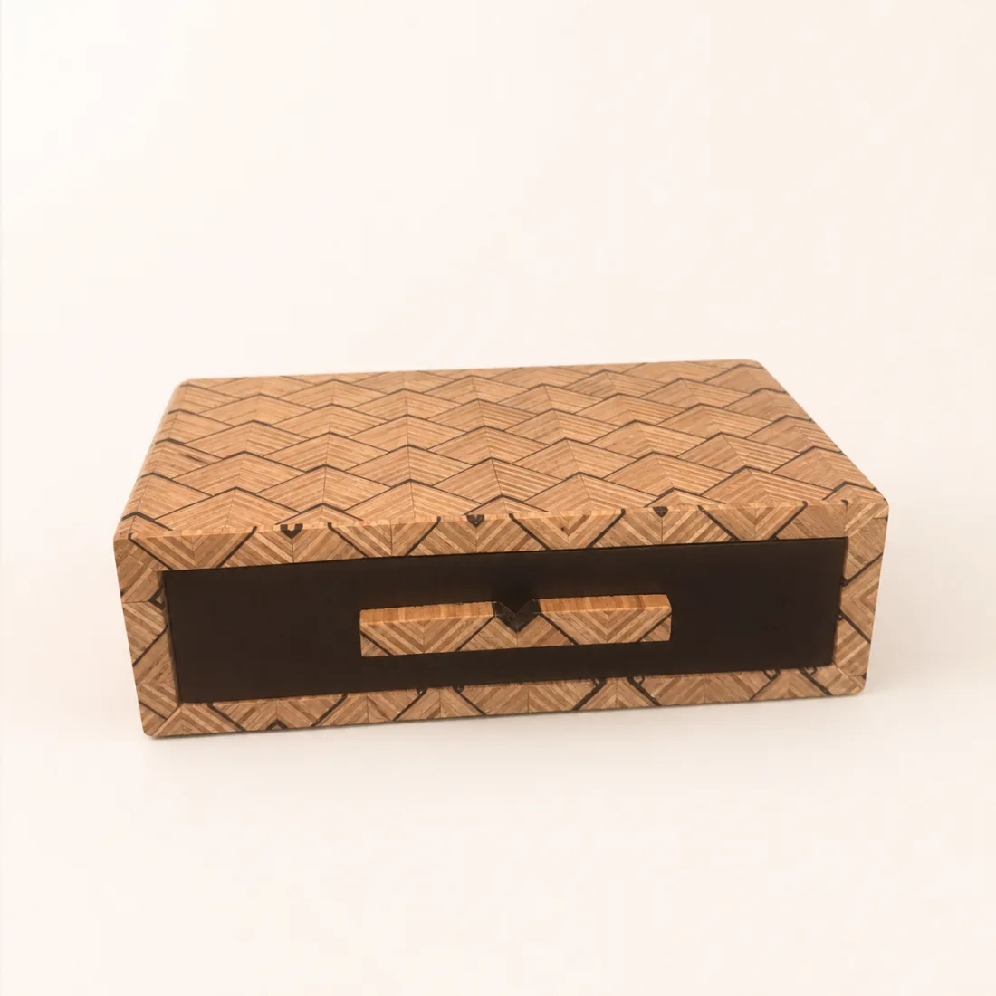 Long patterned wooden box with a closed dark pull-out drawer and matching handle
